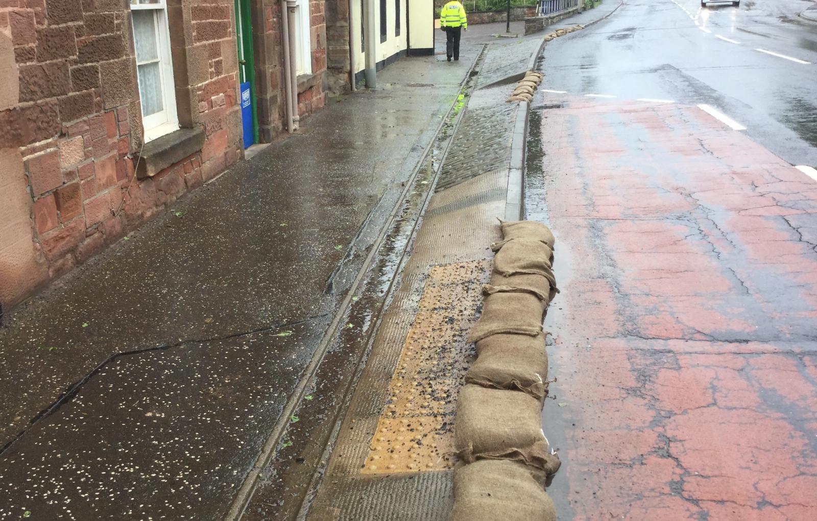 Sandbags and floodgate in use flooded road
